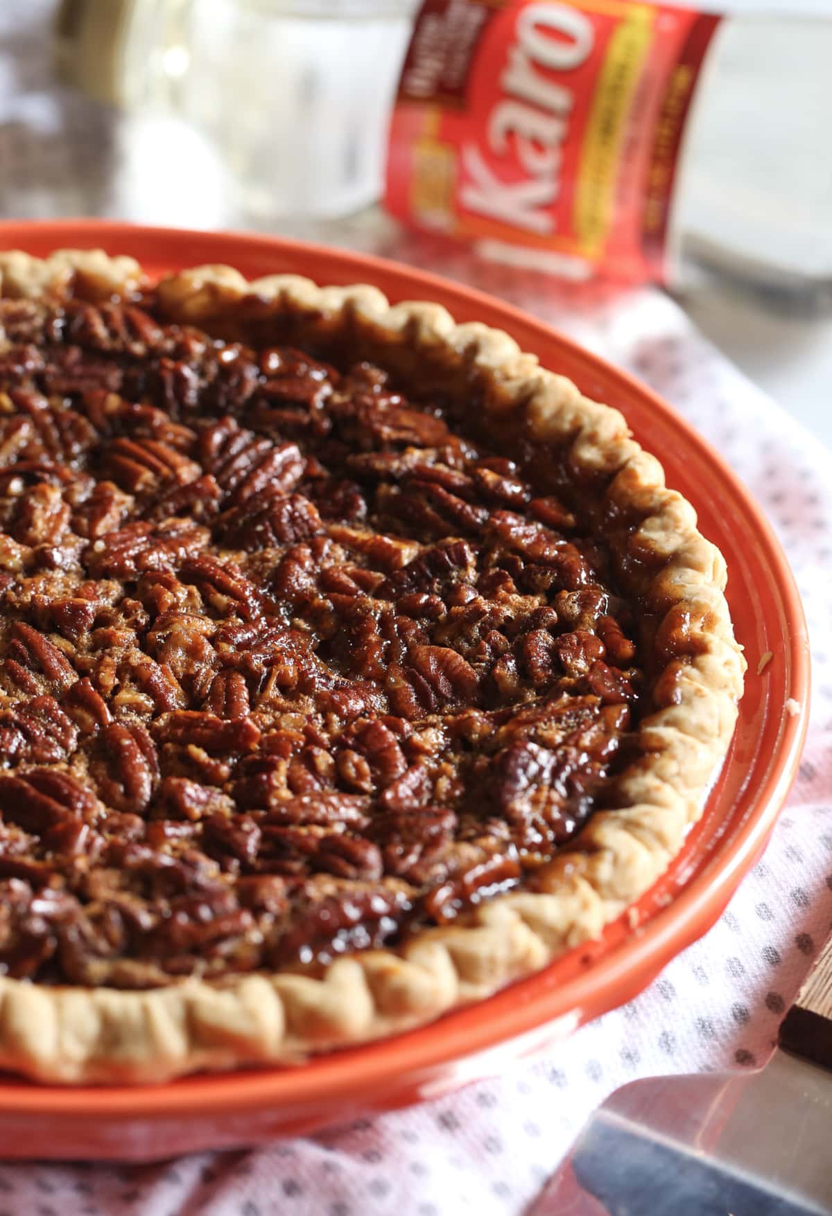 A whole baked pecan pie in an orange pie plate