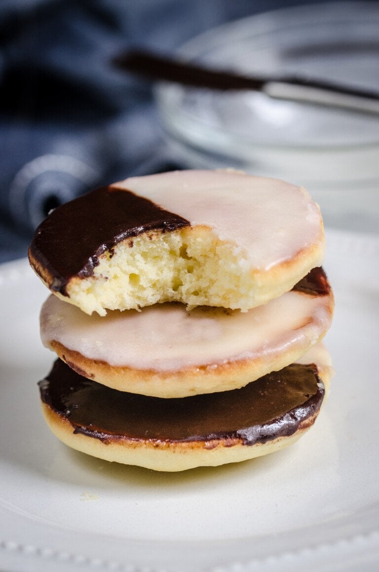 A stack of black and white cookies, with a bite missing from the top cookie.