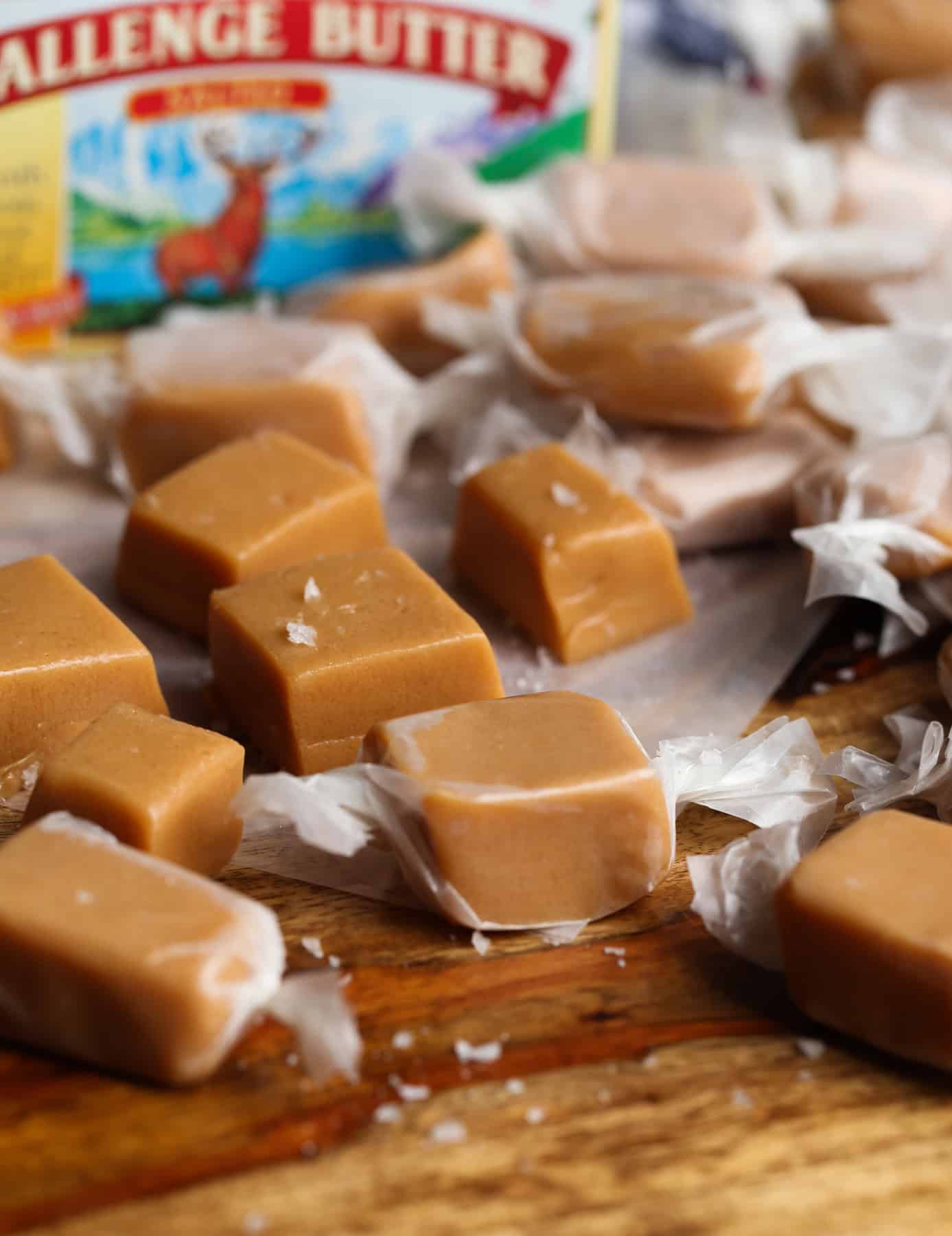 Assorted caramel candy made from scratch, wrapped and arranged on a wood surface.