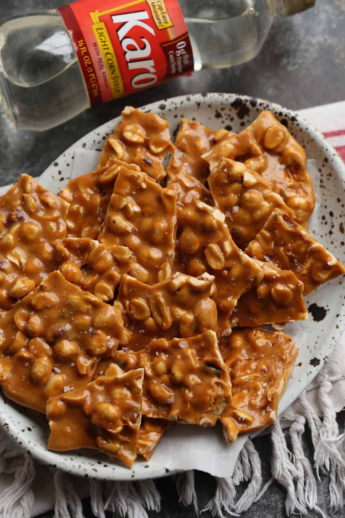 Crunchy peanut butter on a plate next to a bottle of Karo Corn Syrup.