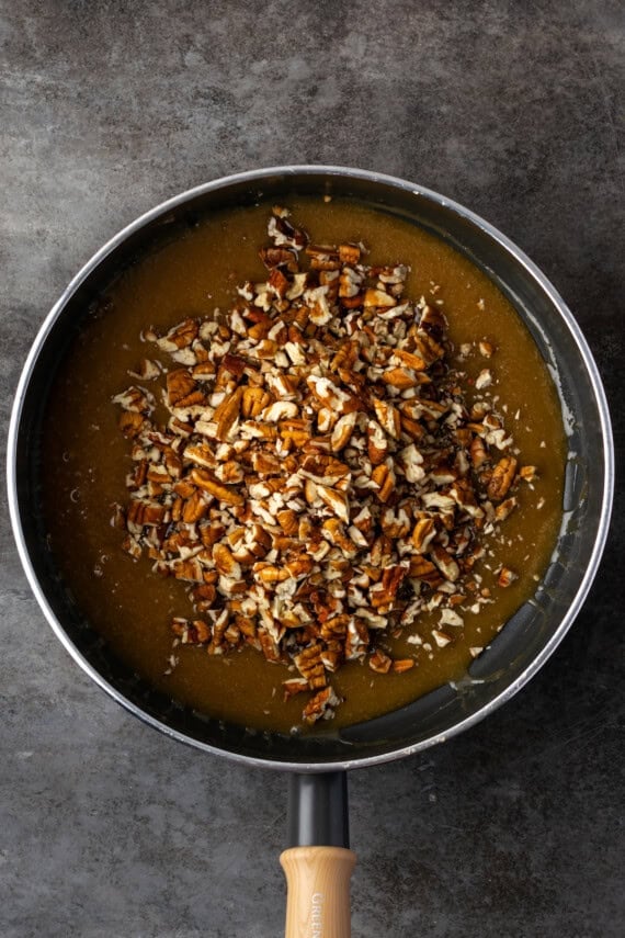 Pecans added to praline mixture in a skillet.