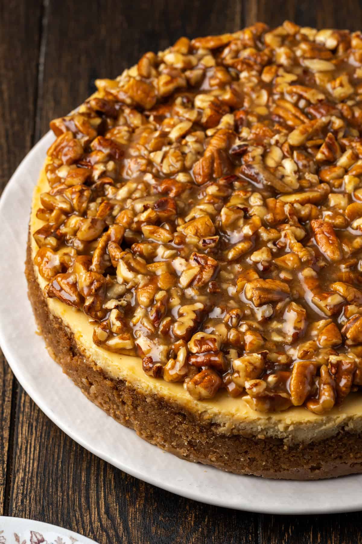 A whole pecan pie cheesecake on a white plate.