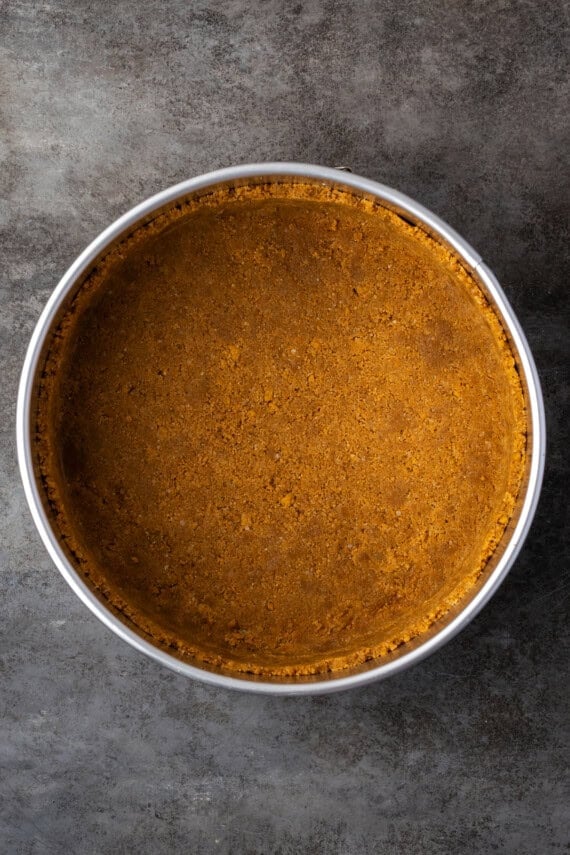 Graham cracker crust pressed into the bottom of a round springform pan.