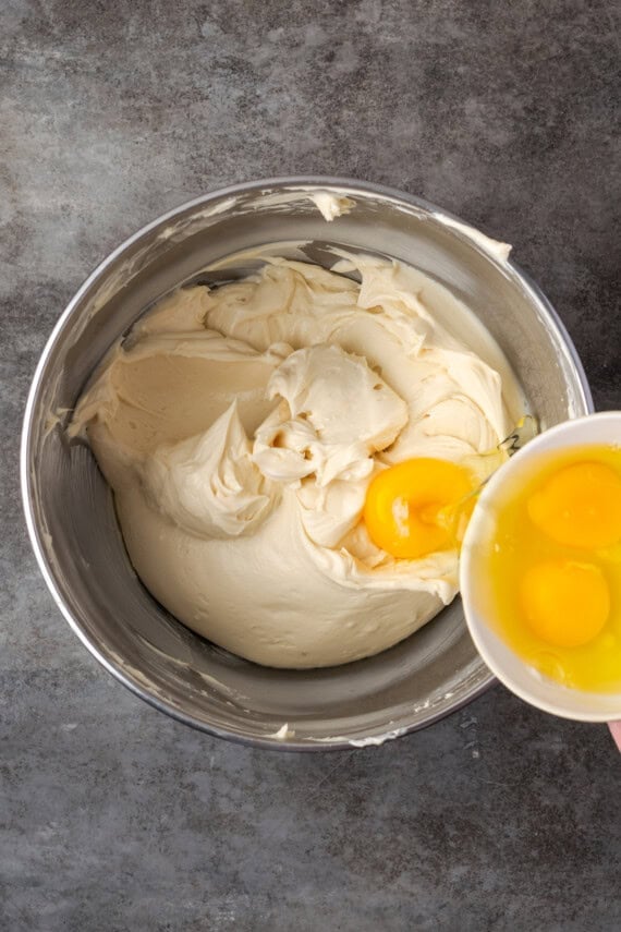 Eggs added into a bowl of cheesecake batter.