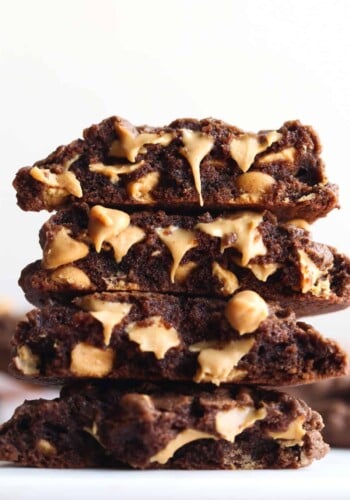 Stacked chocolate cookies broken in half showing melty peanut butter chips on the inside.