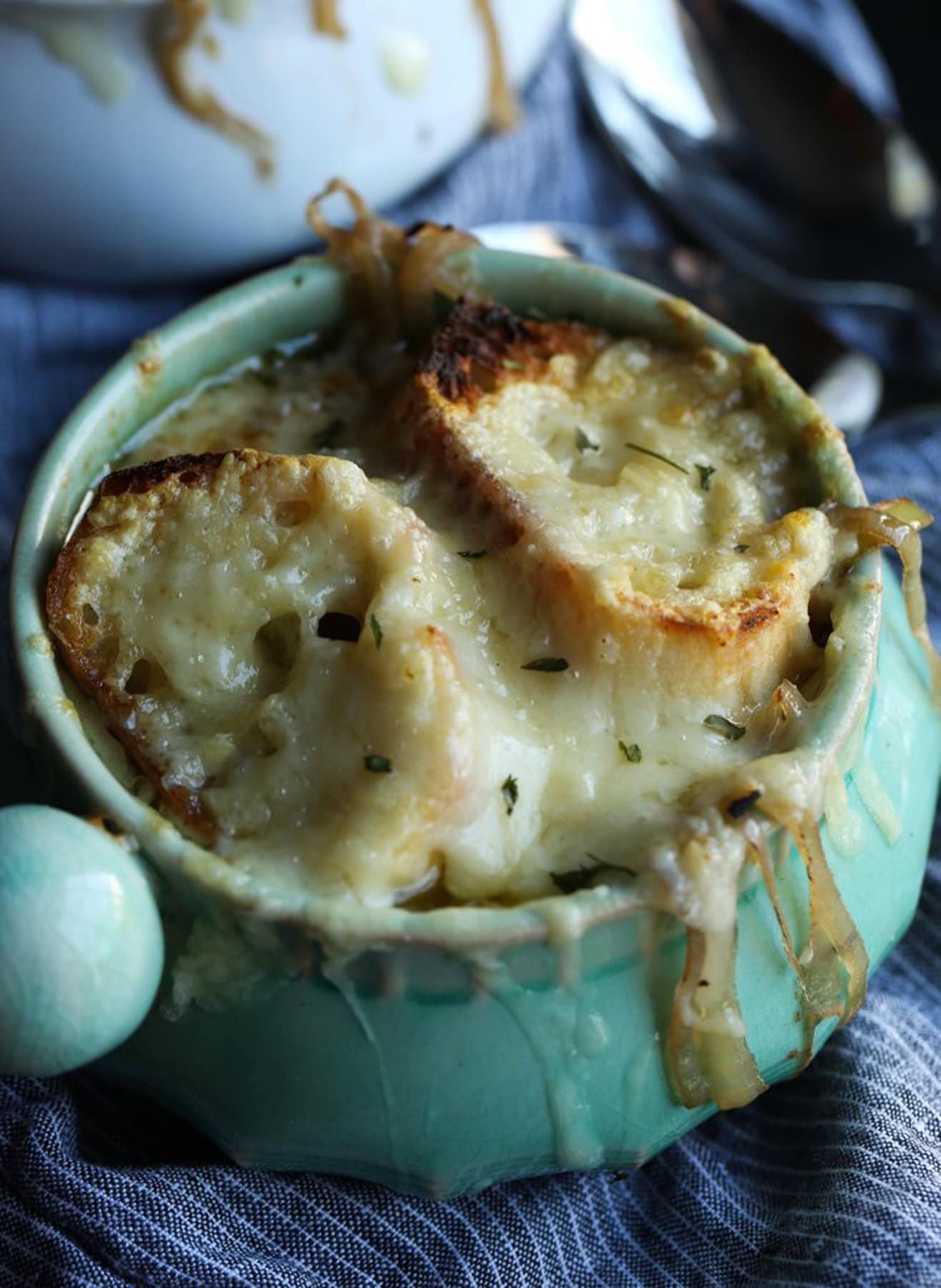 Top view of a ramekin full of French onion soup, topped with bread slices and melted Gruyere cheese.