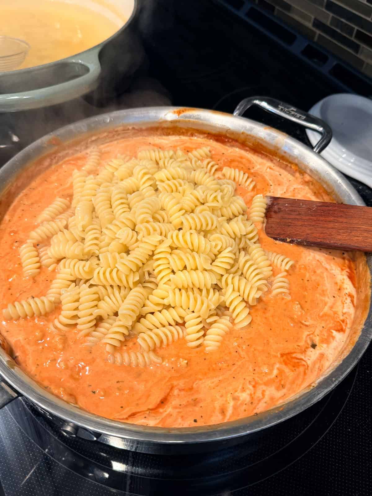 This easy beef pasta recipe is a one-pan dinner made in 30 minutes! Packed with juicy ground beef, cheese, and pasta in creamy tomato sauce. Pasta added to creamy beef sauce in a skillet.