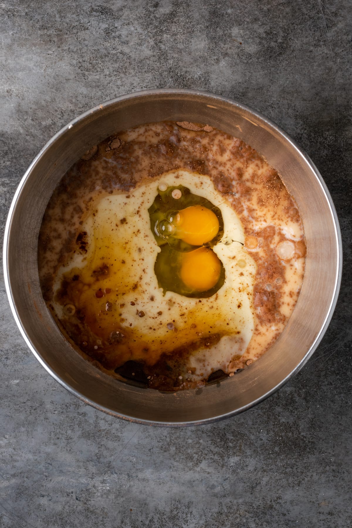 Wet ingredients and eggs added to dry ingredients in a mixing bowl.