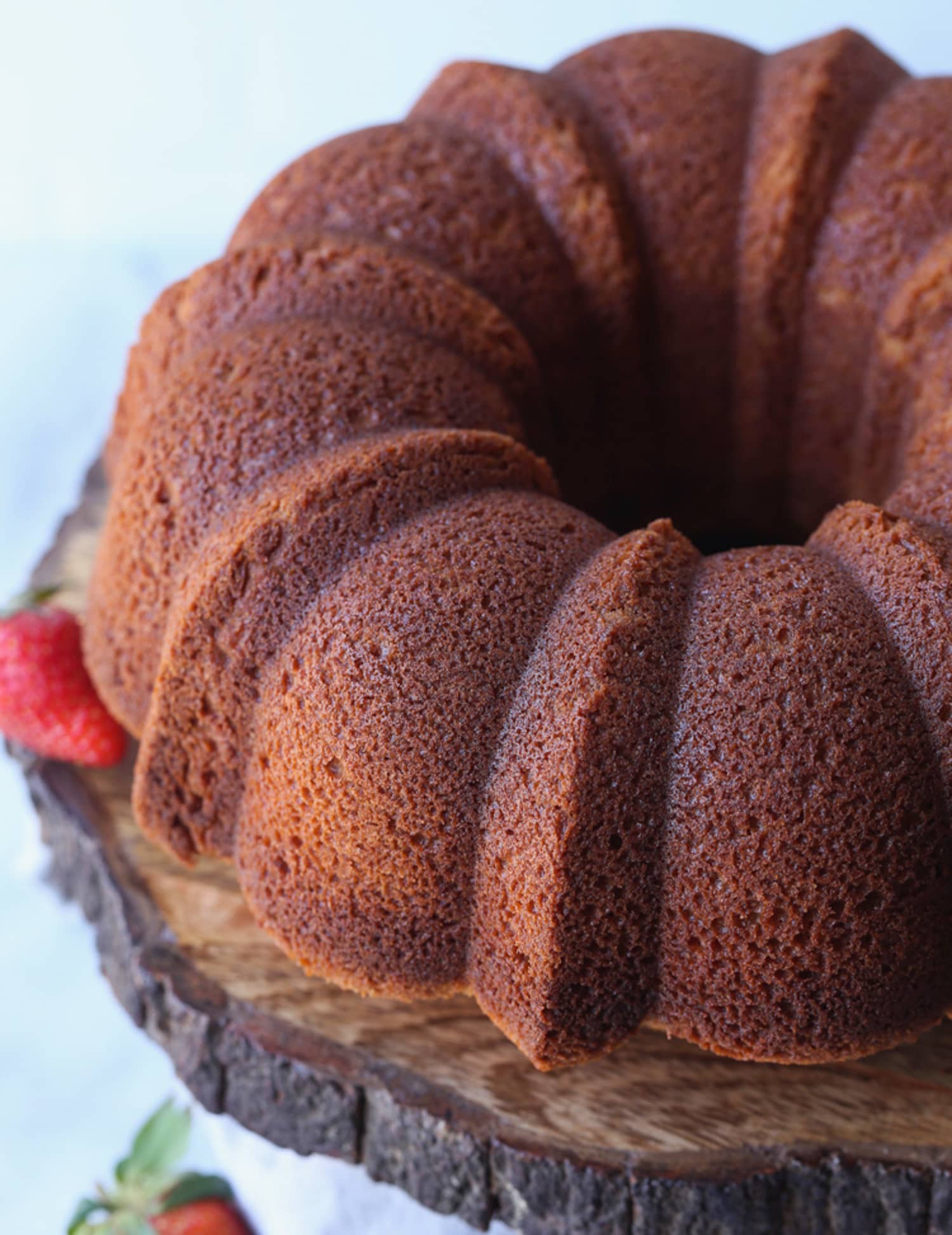 A pound cake baked in a bundt pan turned over on a wooden cake pedestal.