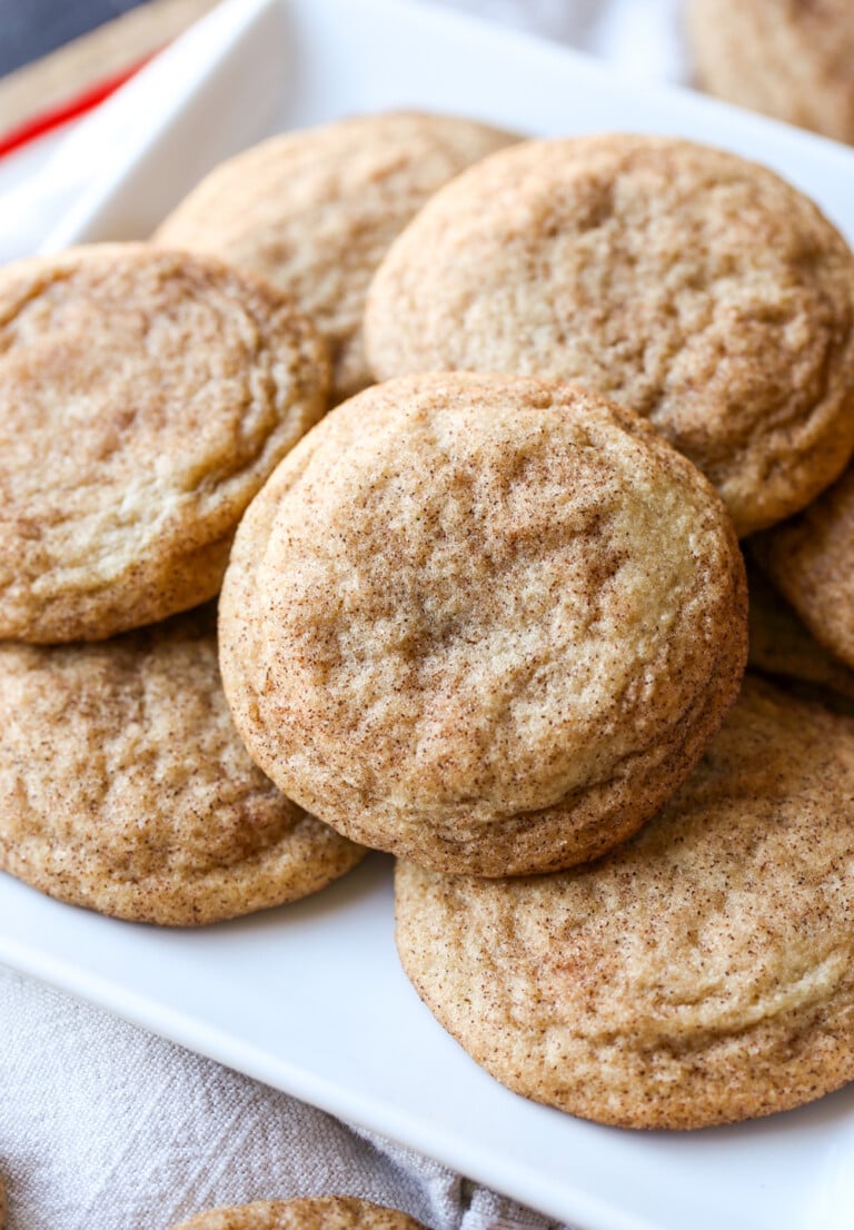 Snickerdoodle cookies stacked in a pile on a white plate.