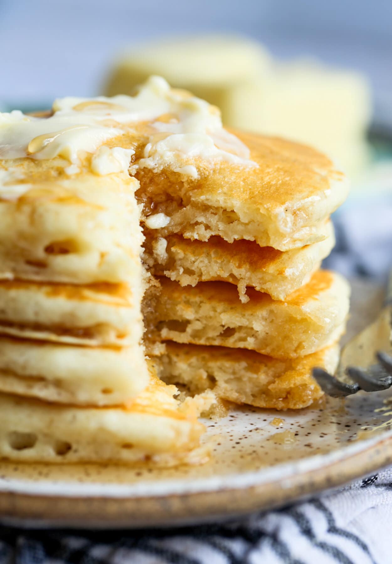 Buttermilk Pancakes stacked with a portion cut out showing the insides of the pancakes