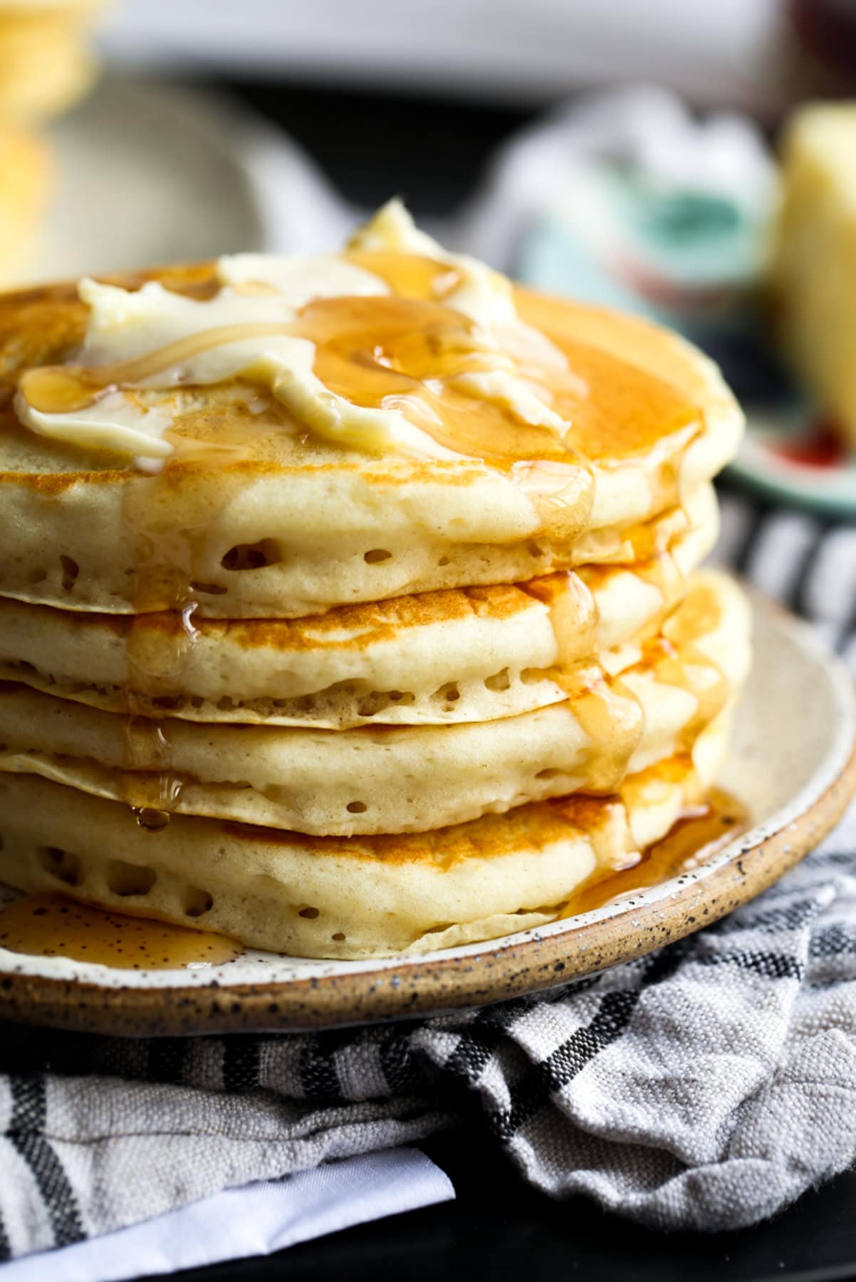 Buttermilk Pancakes stacked on a plated topped with butter and maple syrup