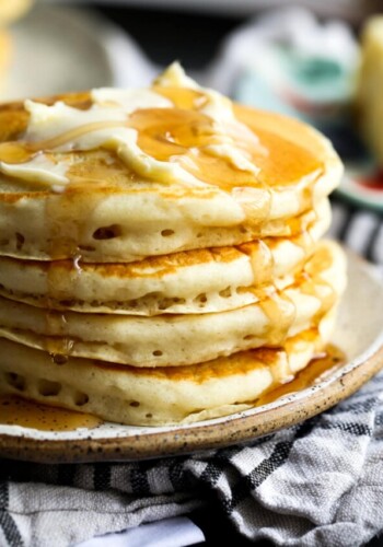 Buttermilk Pancakes stacked on a plated topped with butter and maple syrup