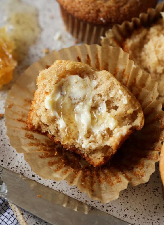 Easy Honey Wheat Muffins spread with butter and drizzled with honey