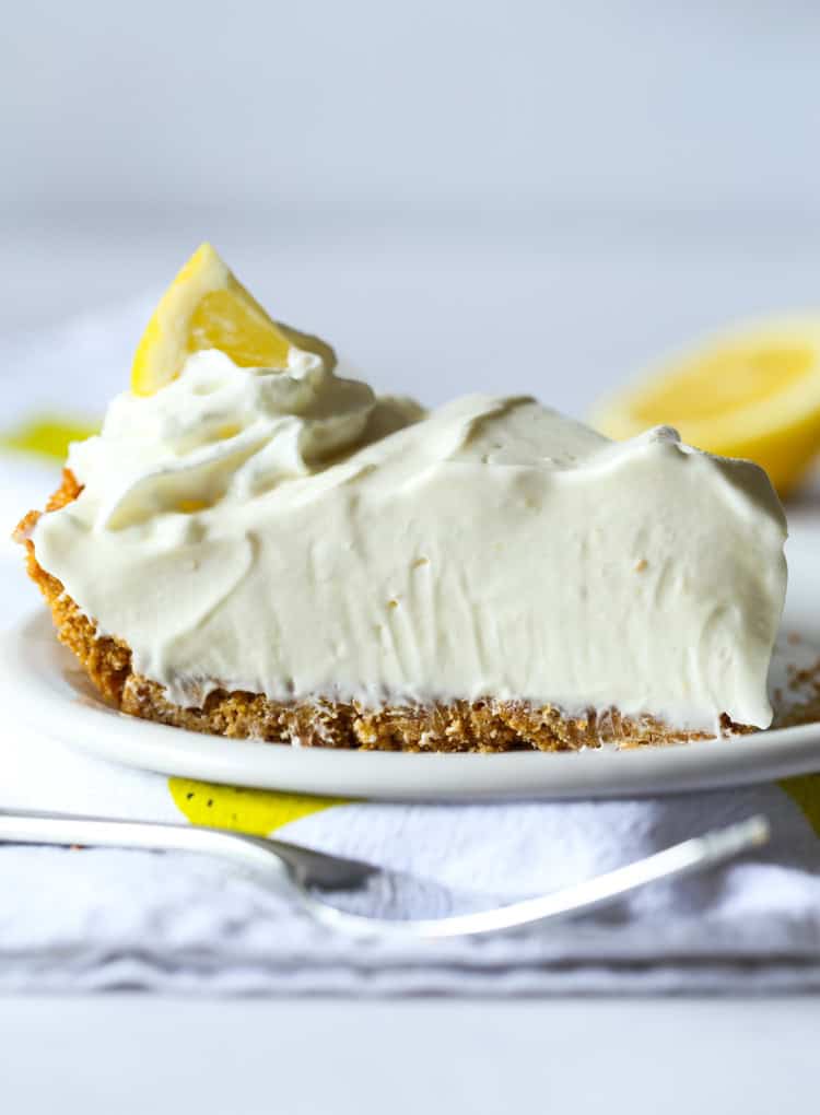 A slice of lemonade pie on a plate with a fork in front.