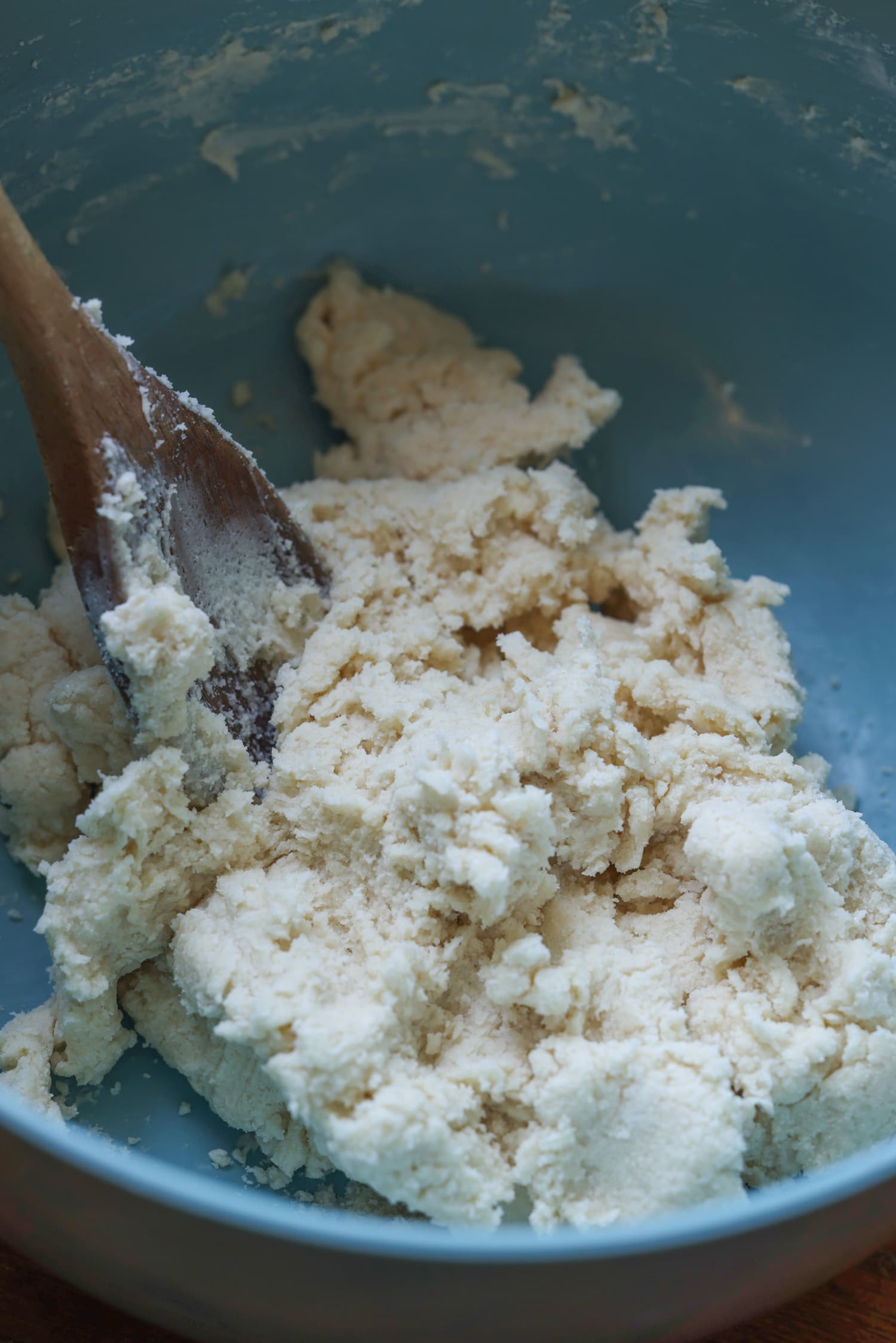 biscuit dough in a blue bowl with a wooden spoon