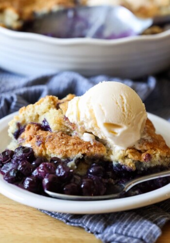 A scoop of blueberry cobbler on a white plate with vanilla ice cream on top
