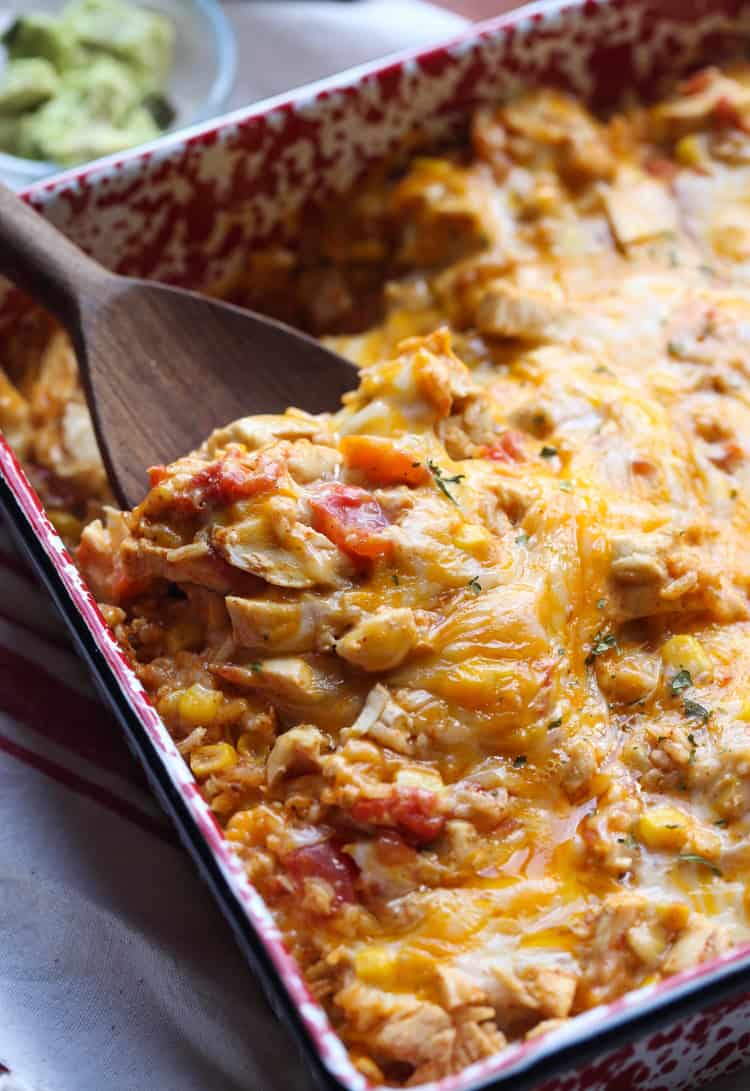 A serving spoon scooping into a baked fiesta chicken casserole.