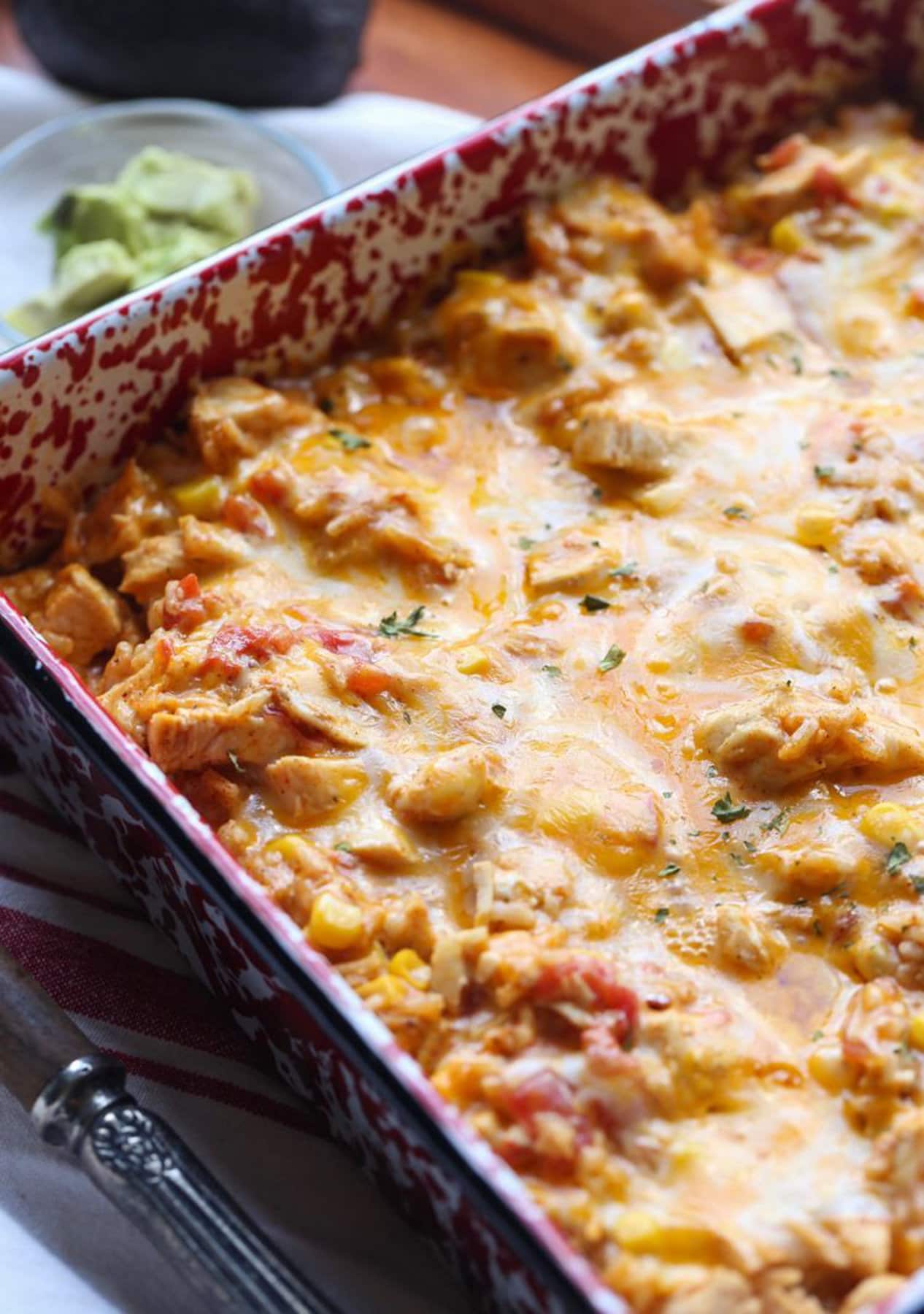 This fiesta chicken casserole is an easy Tex-Mex dinner recipe loaded with leftover shredded chicken, tender rice, sweet corn, and cheese. Cheesy fiesta chicken casserole in a baking pan.