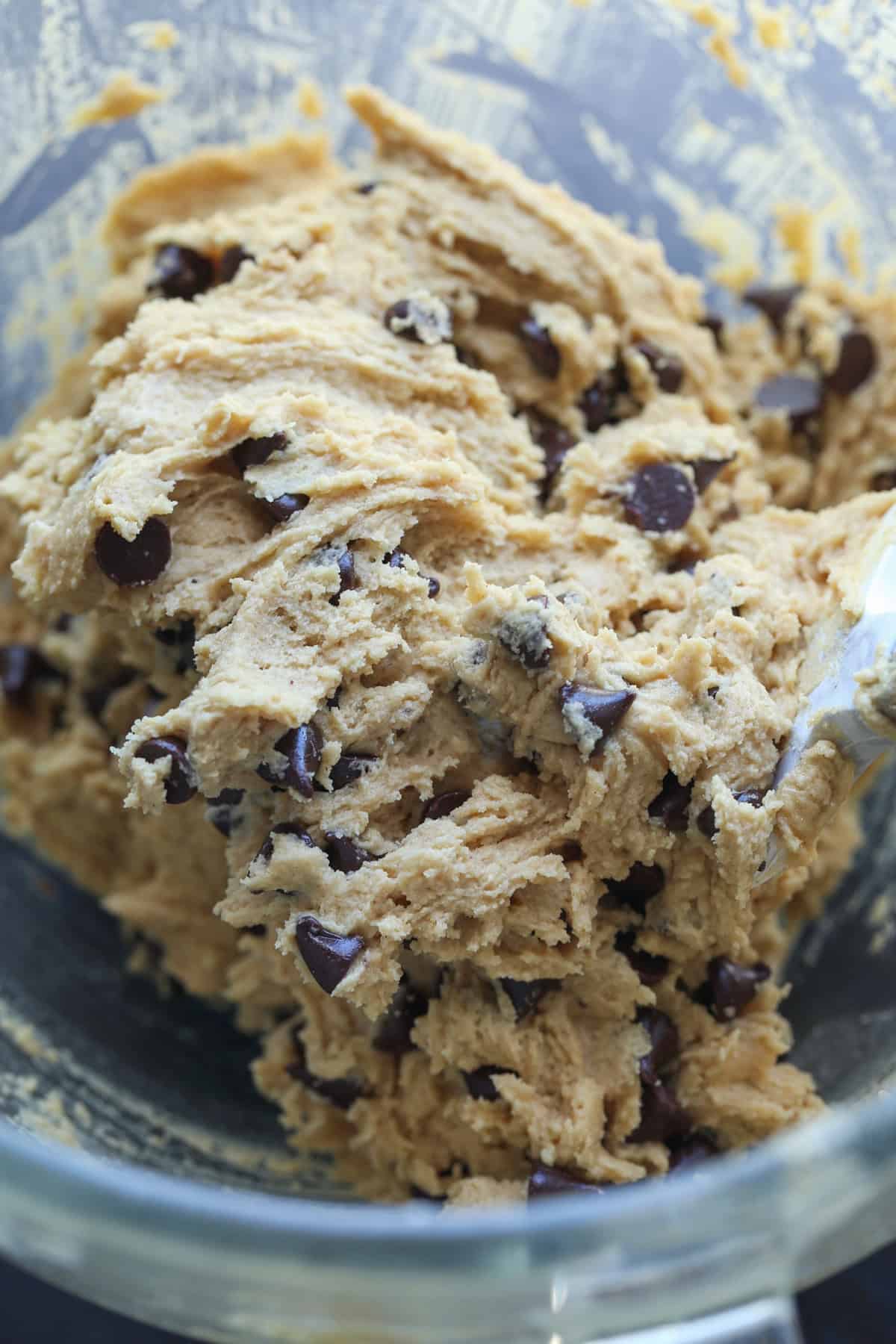 Peanut butter cookie dough with chocolate chips in a clear mixing bowl