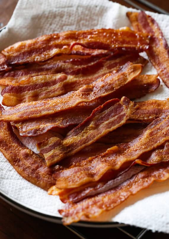 A cutting board with bacon, cheese, and green onions
