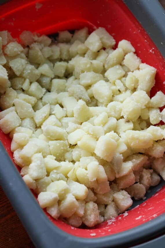 A red and black container filled with chopped potatoes