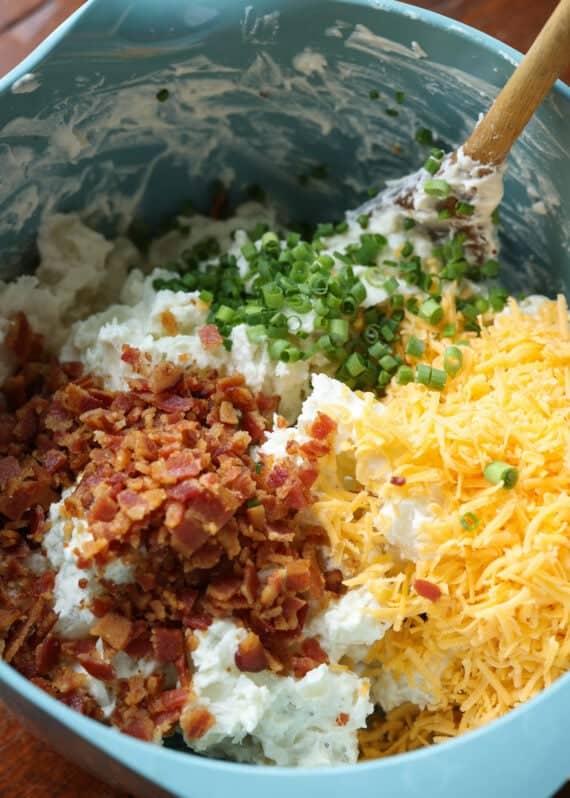 A bowl filled with cheese, bacon and green onions
