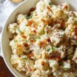 A bowl of loaded potato salad with bacon and chives