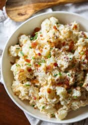 A bowl of loaded potato salad with bacon and chives