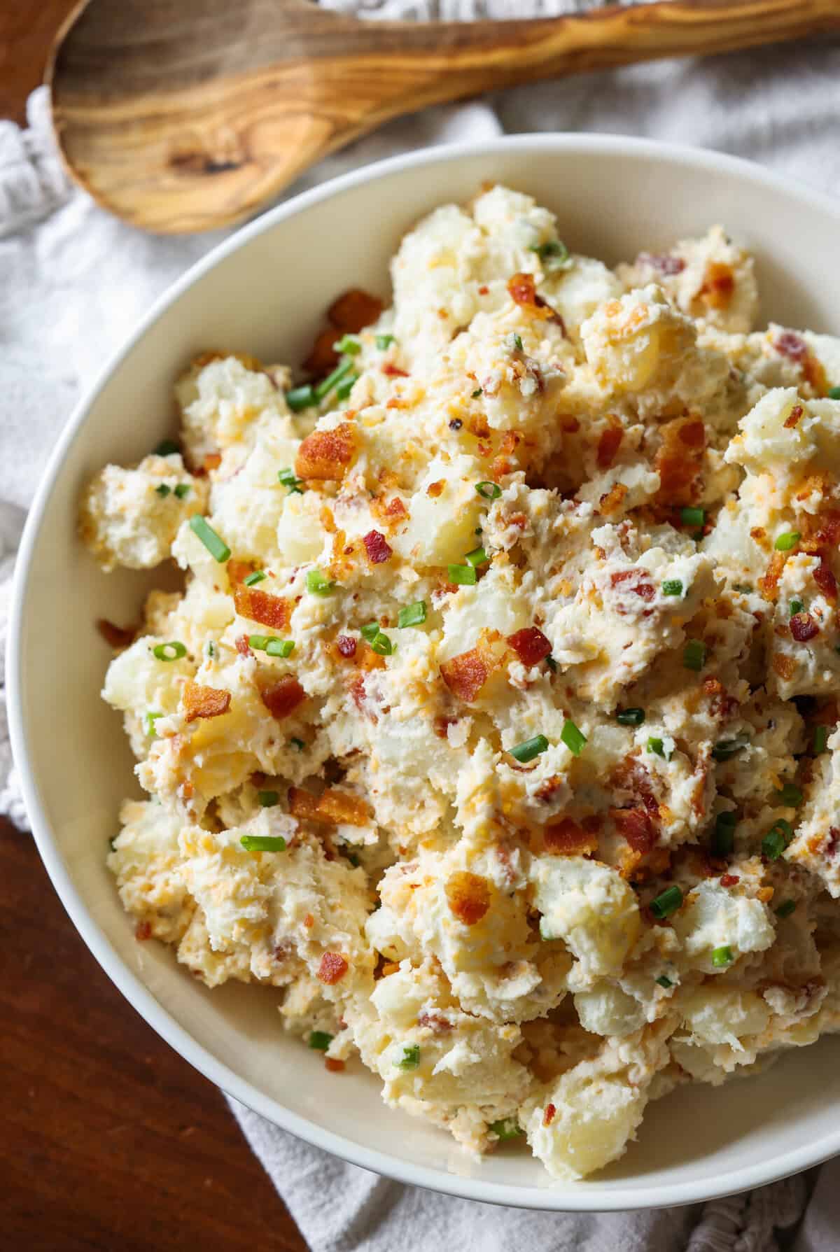 A bowl of loaded potato salad with bacon and chives