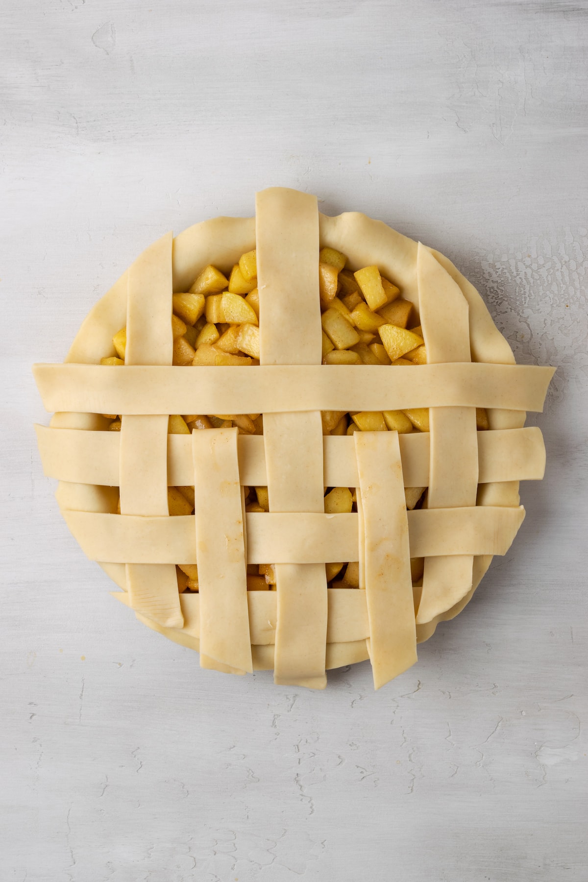 An apple pie with a partially completed lattice top.
