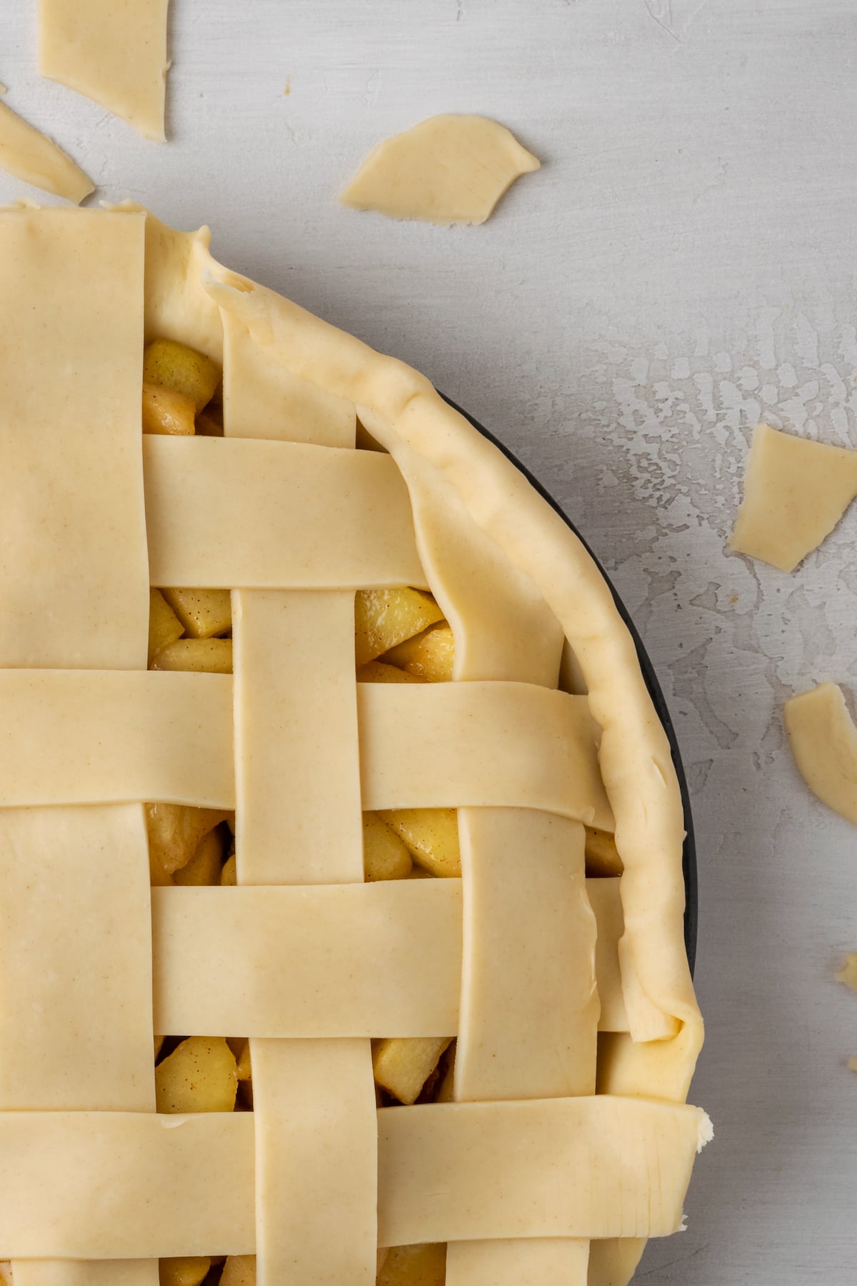 Close up of an apple pie with a lattice top with the ends of the lattice strips trimmed.