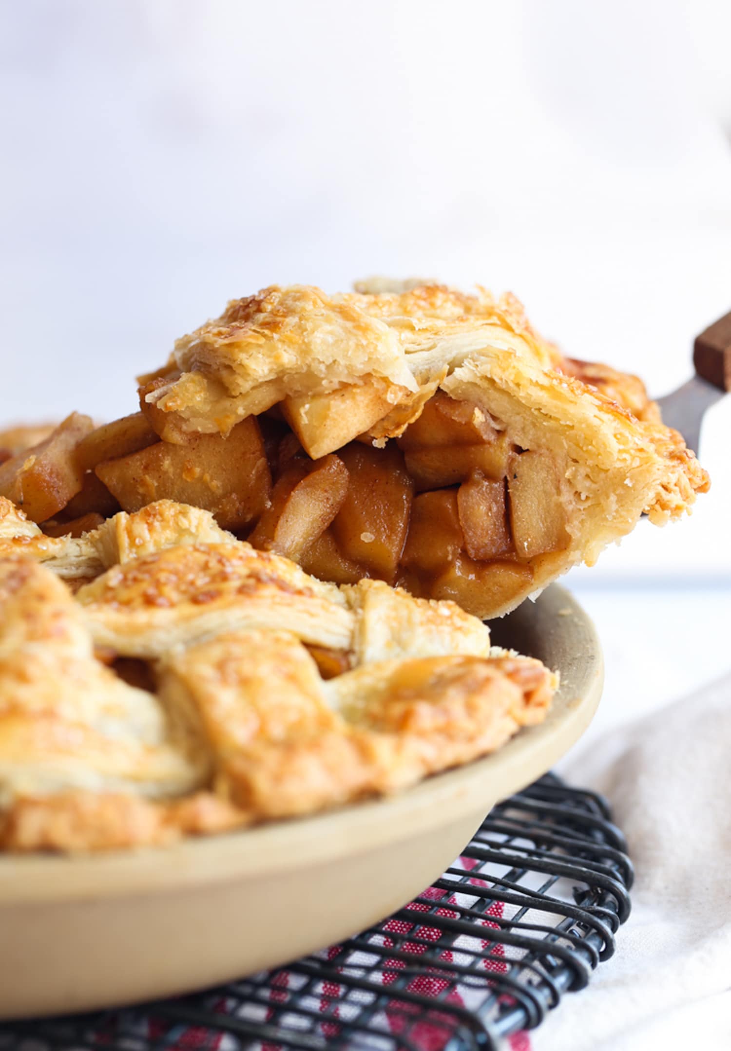 A pie server serving a slice of apple pie from a pie plate