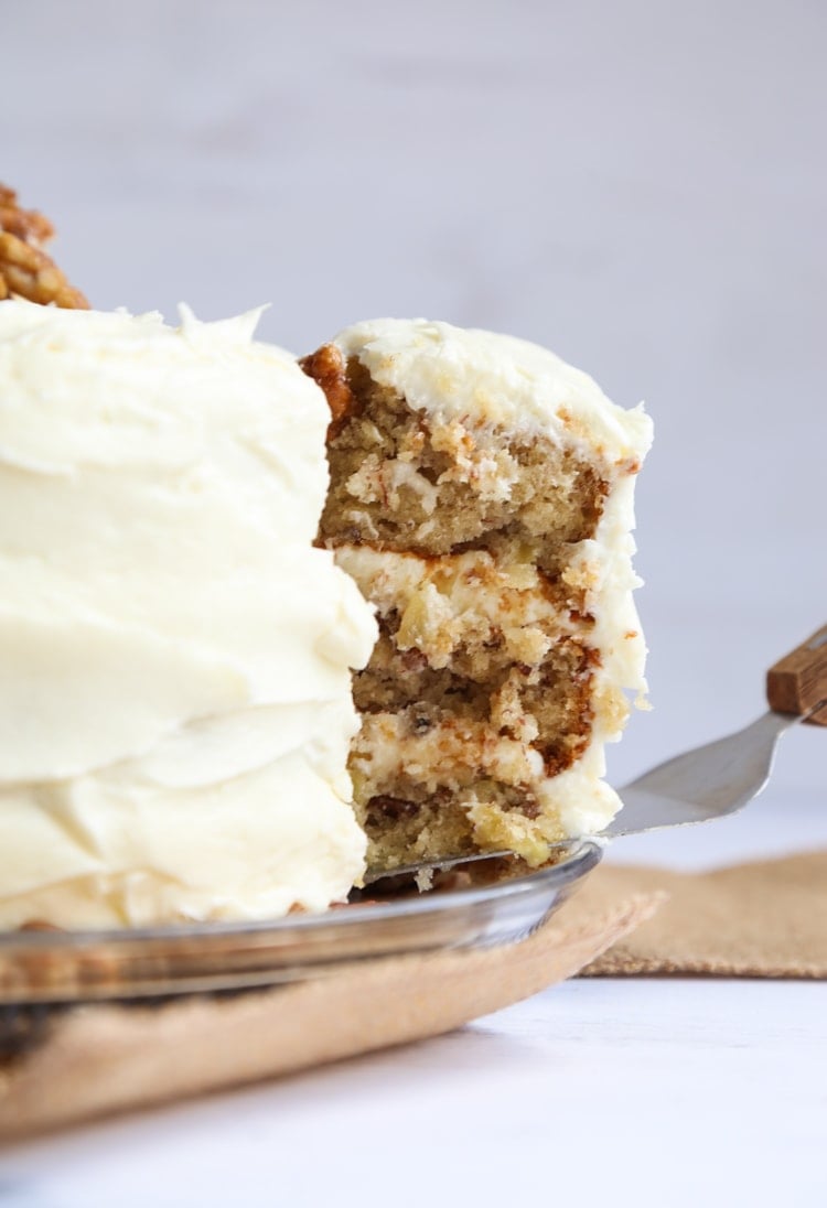 Side view of a slice of cake being lifted from a frosted Hummingbird Cake.