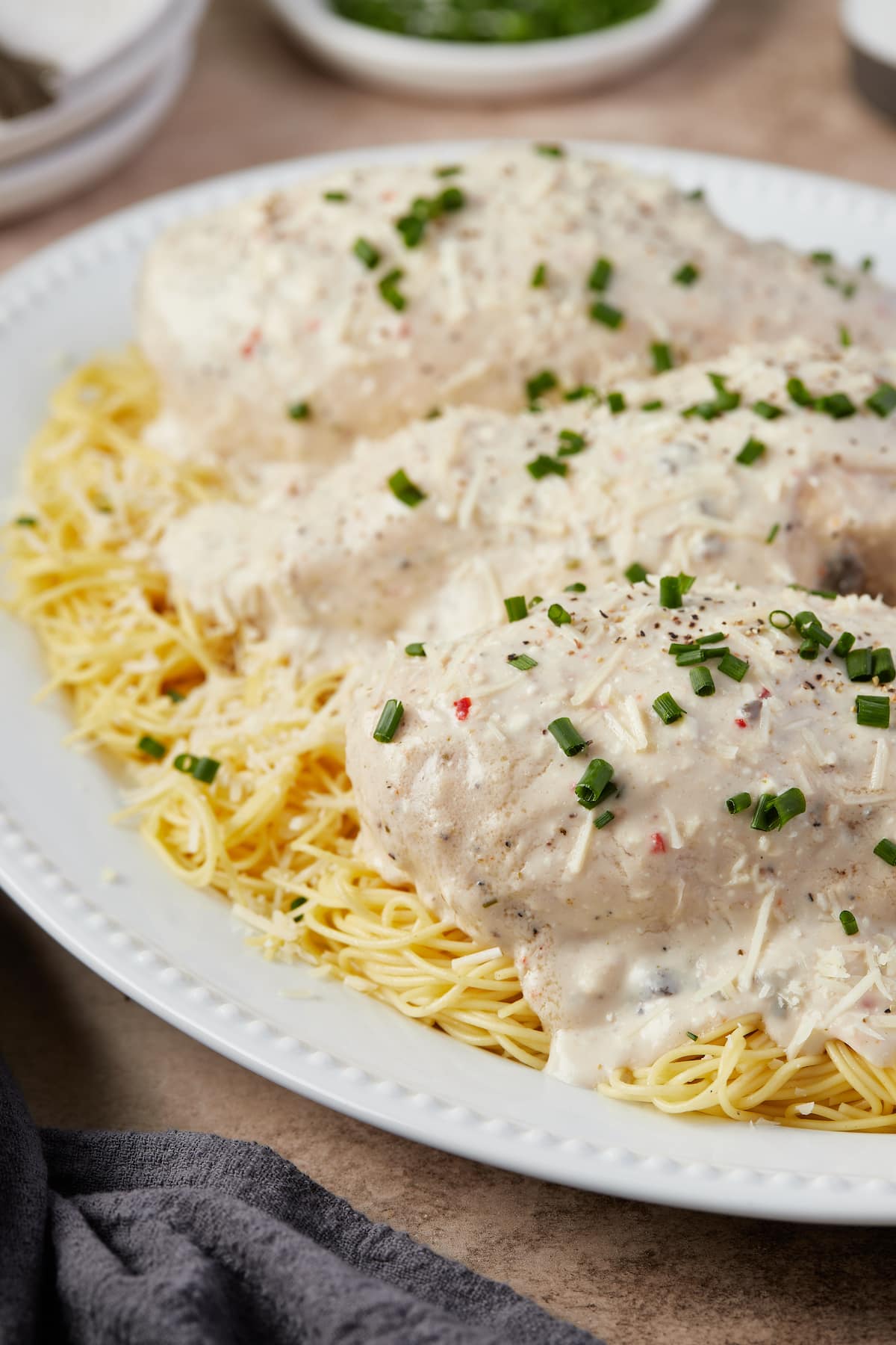 Baked creamy chicken served over angel hair pasta on a plate.