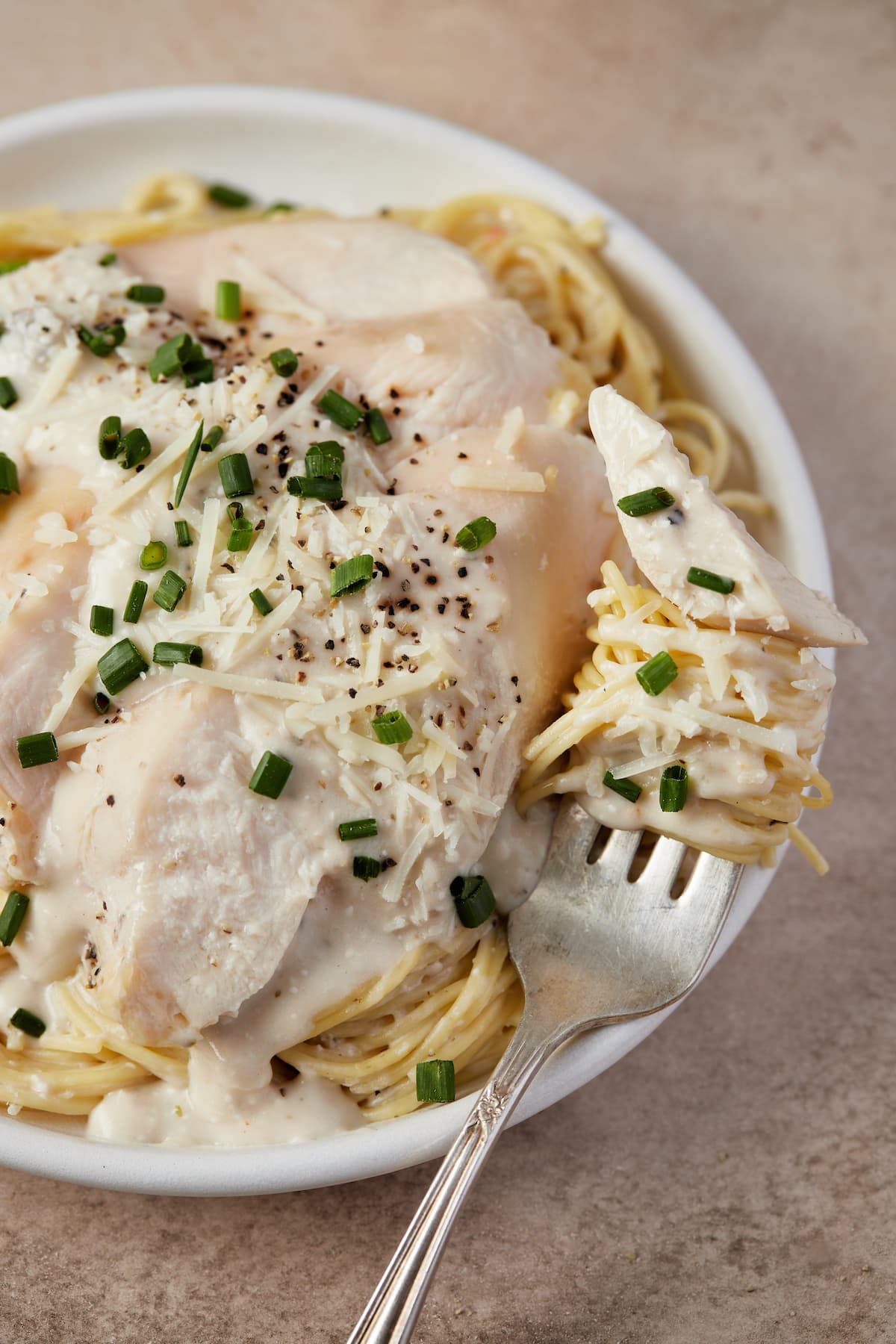 Creamy chicken pasta on a plate with a forkful.