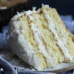 A slice of frosted coconut cake on a plate.