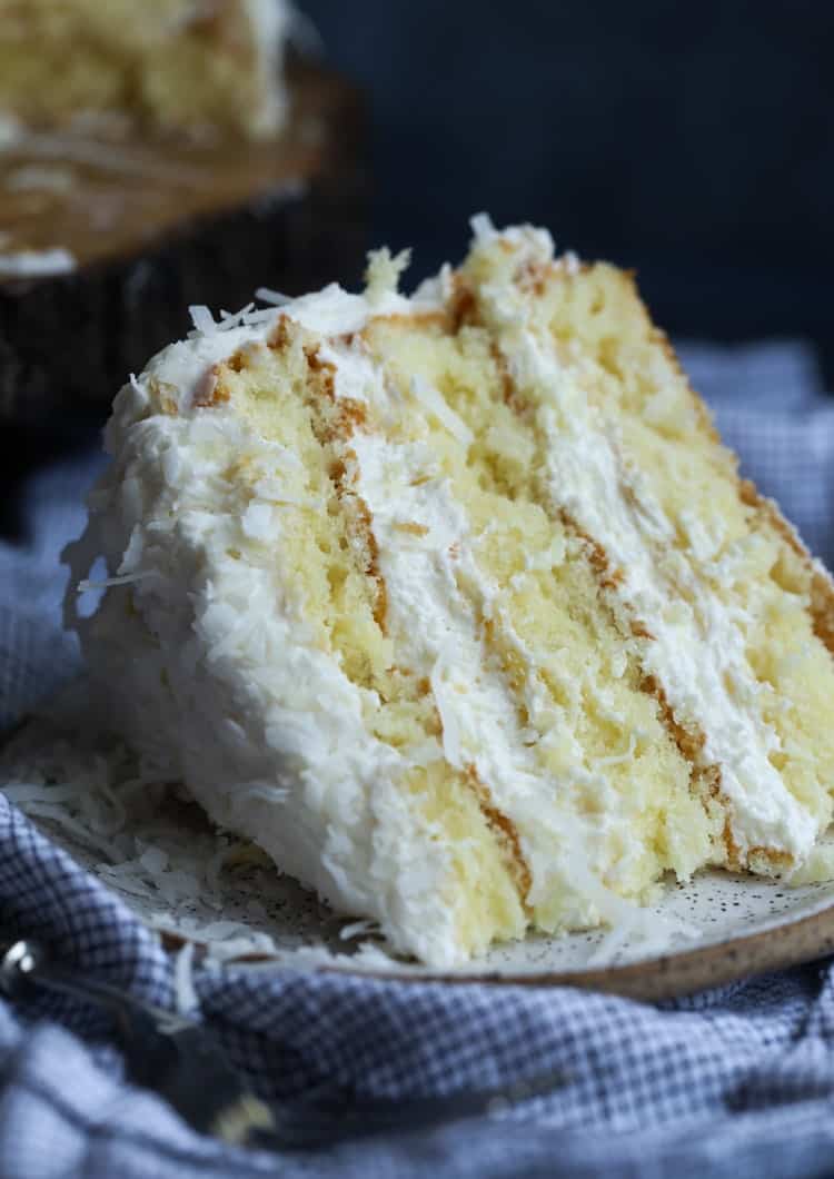 A slice of frosted coconut cake on a plate.