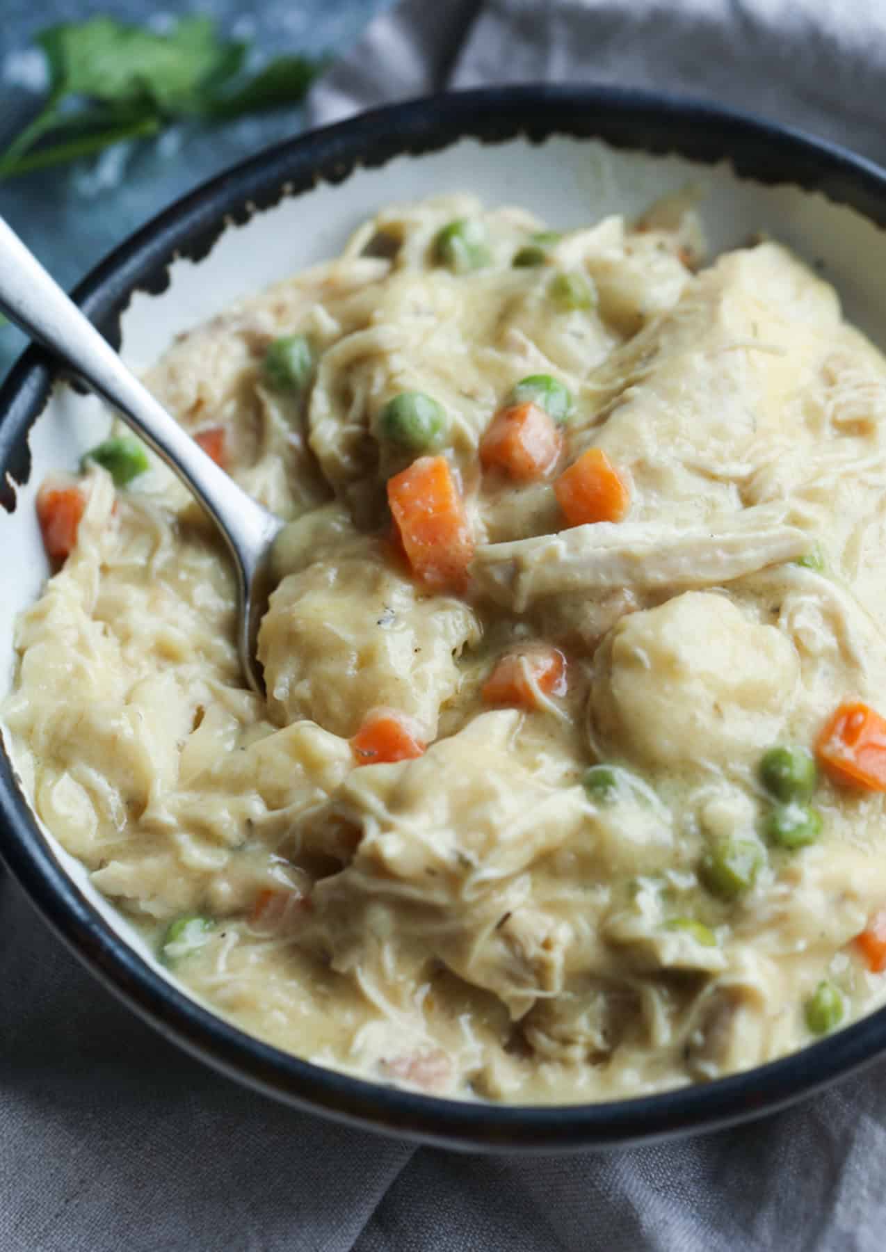 A bowl of chicken and dumplings with a spoon