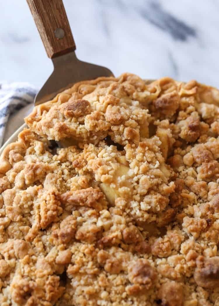 A slice of Dutch apple pie is lifted from a pie plate.