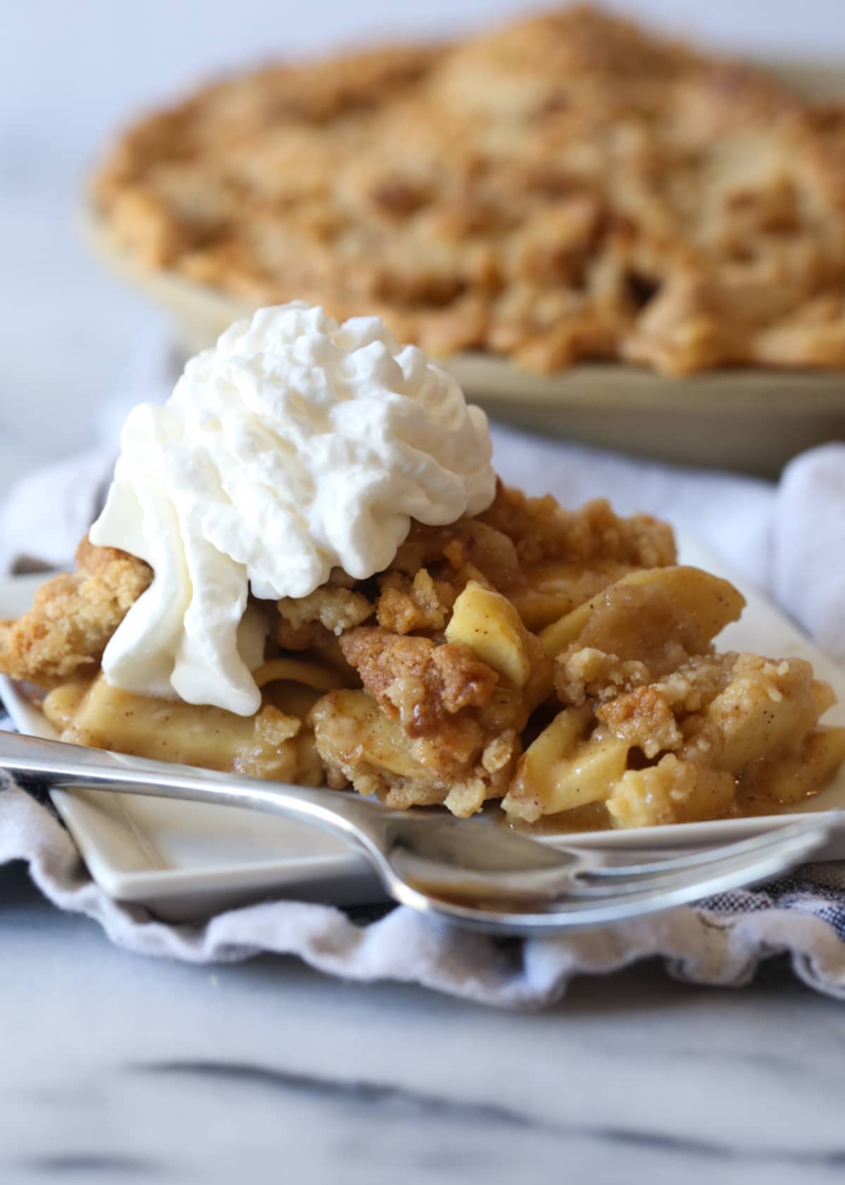 A slice of Dutch apple pie topped with whipped cream