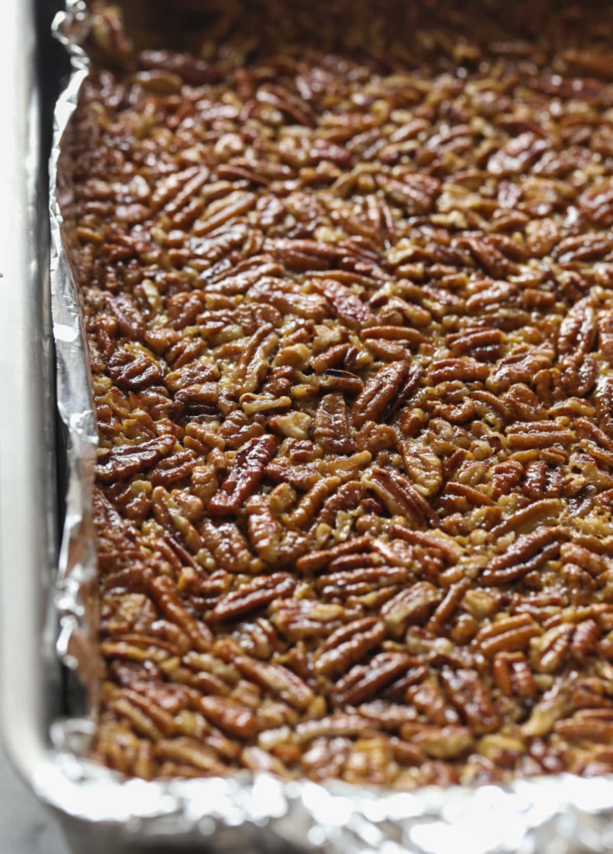 Baked pecan pie bars in a foil lined baking sheet