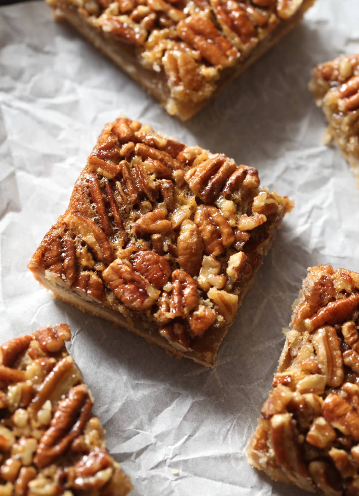 Pecan pie squares cut on a piece of parchment paper.