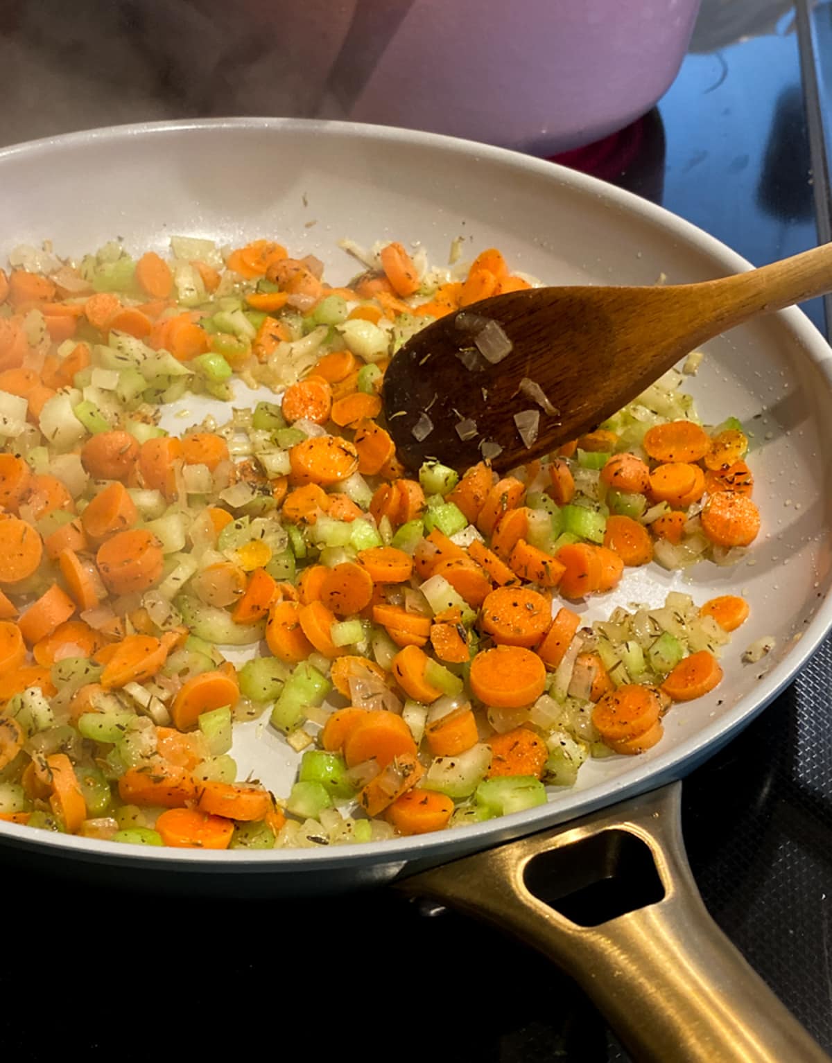एक कड़ाही में गाजर, प्याज और अजवाइन को लकड़ी के चम्मच से भून लें