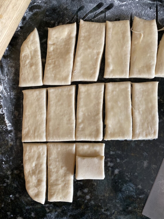 Partially rolled dough rectangles for Parker House rolls.