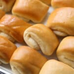 Rows of baked Parker House rolls on a baking sheet.