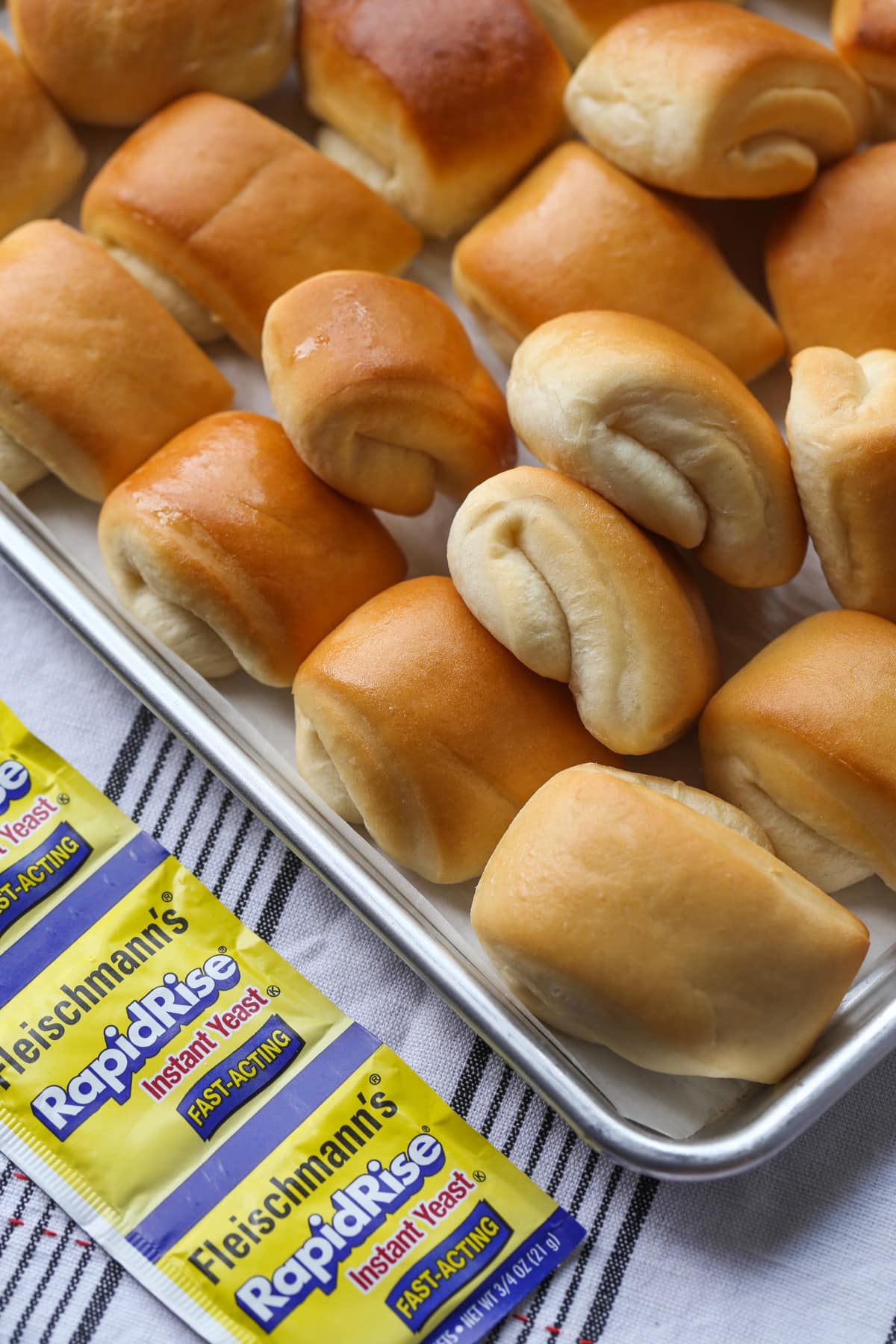 Rows of baked Parker House rolls on a baking sheet.