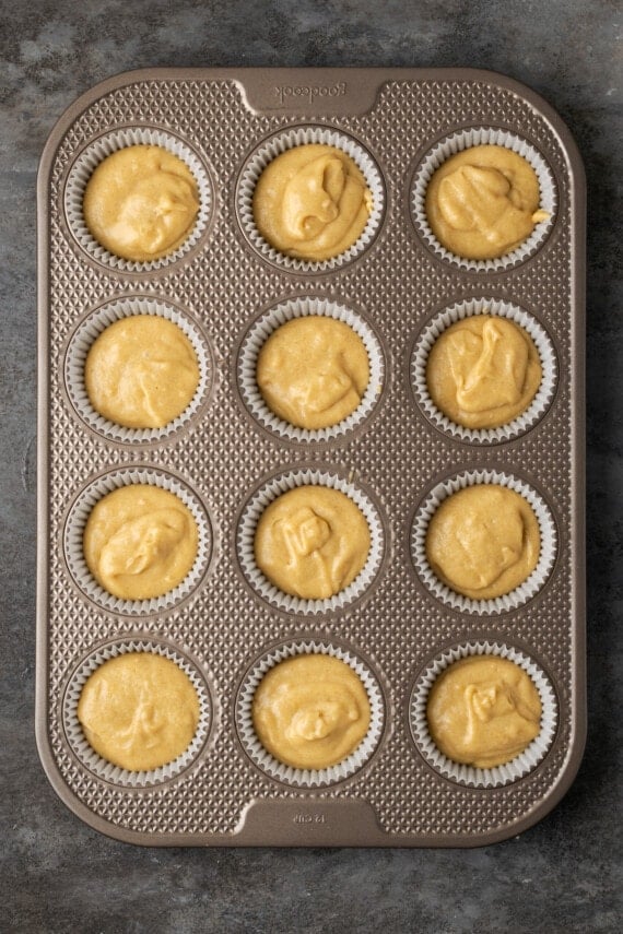 Overhead view of a lined metal cupake pan filled with snickerdoodle cupcake batter.