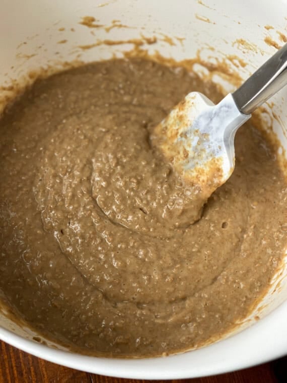 Bran muffin batter in a white bowl with a rubber spatula.