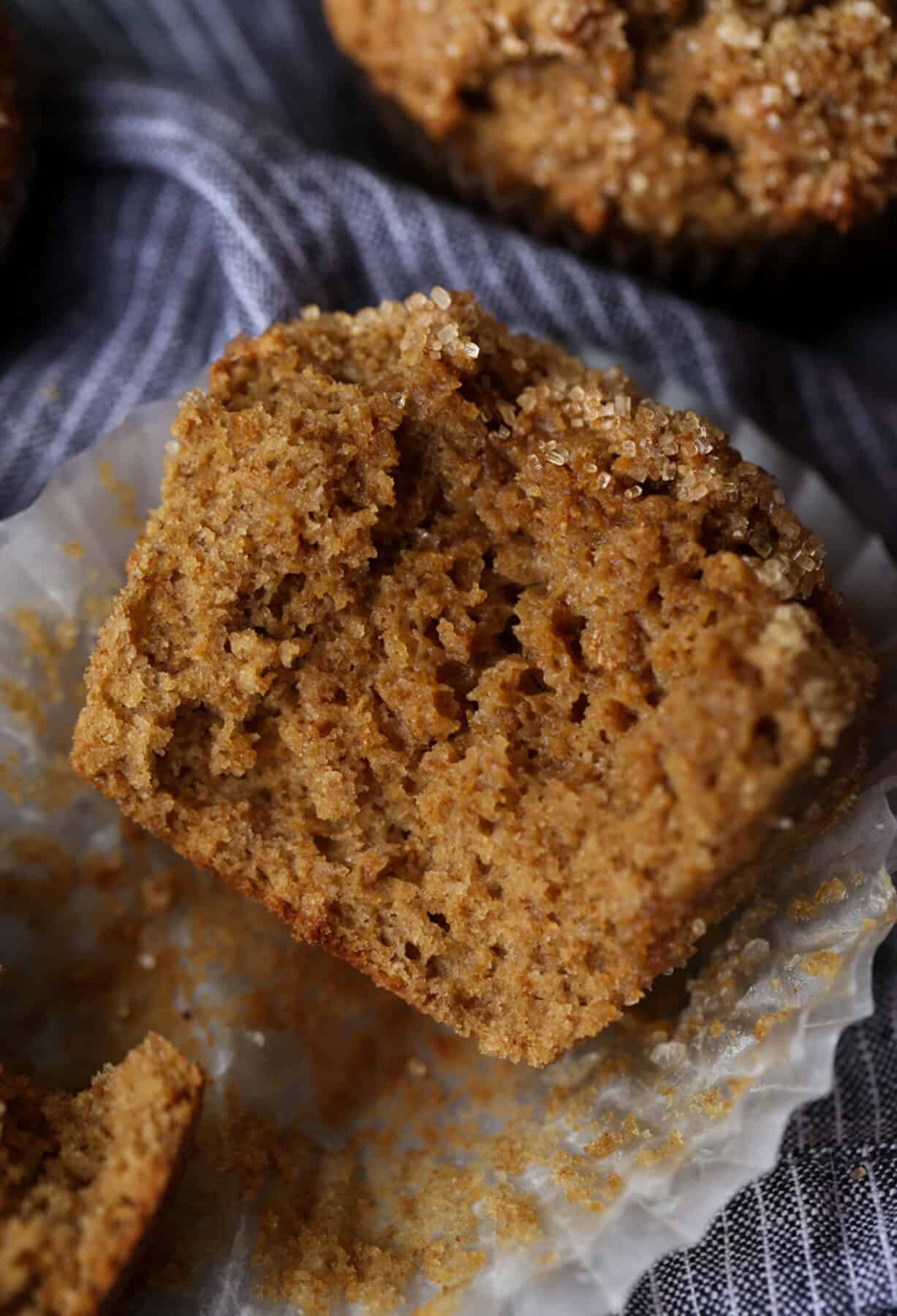 Close up of one half of a bran muffin resting in a paper liner.